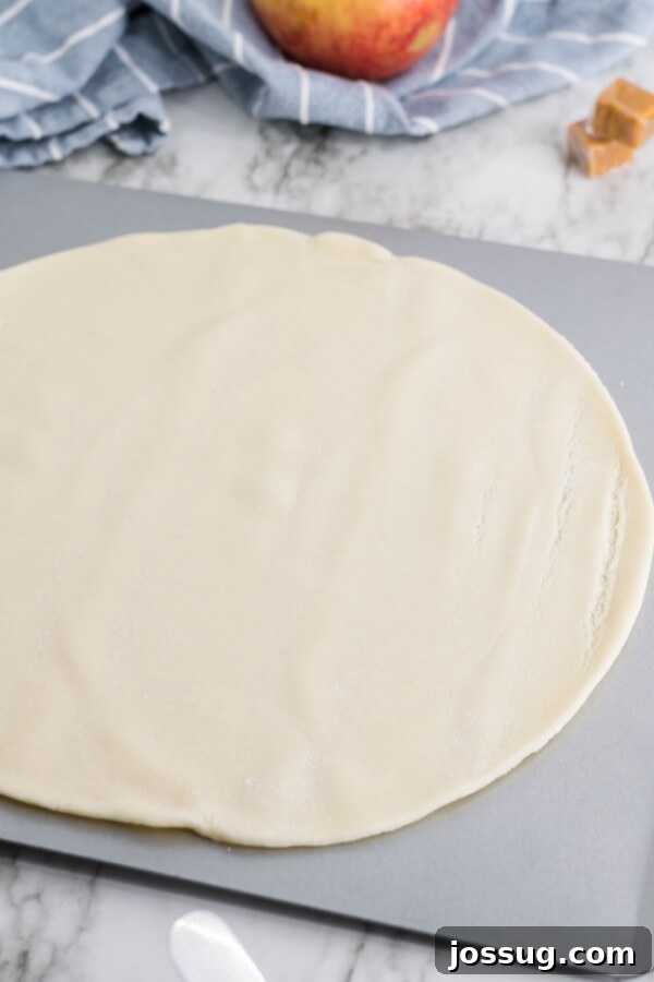 A store-bought pie crust laid flat on a baking sheet, ready for the filling.
