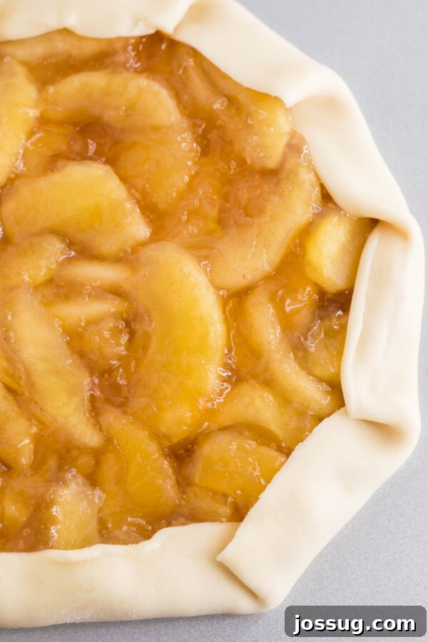 A top-down view of the caramel apple galette before baking, showcasing the folded crust and apple filling.
