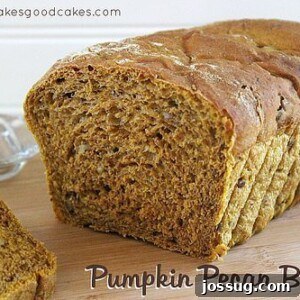 A freshly baked loaf of golden Pumpkin Pecan Bread, sliced to reveal a moist, tender crumb with scattered pecan pieces.