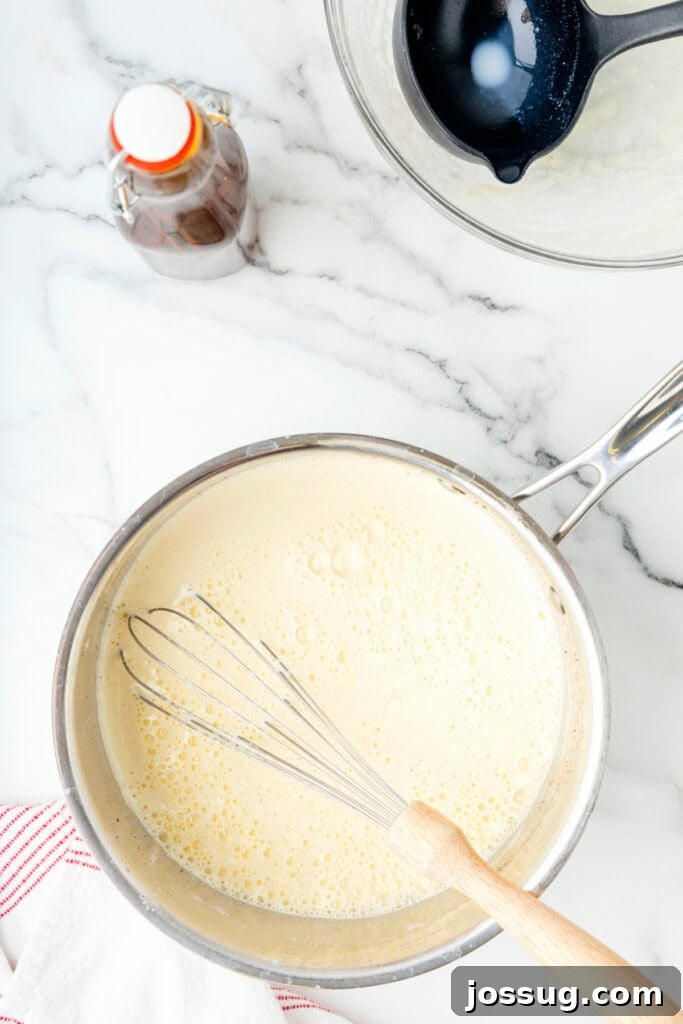 Classic Homemade Eggnog 14 Saucepan with whisk inside, filled with tempered eggnog mixture before thickening.