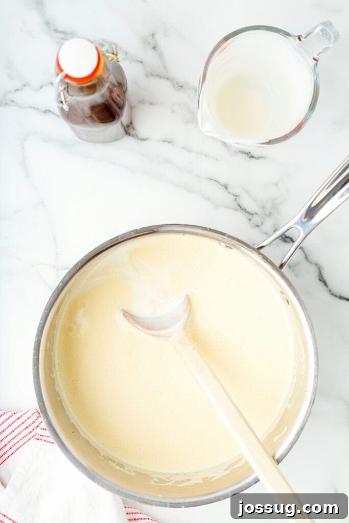 Classic Homemade Eggnog 16 Cooked eggnog in a saucepan with a wooden spoon resting inside, ready for straining.