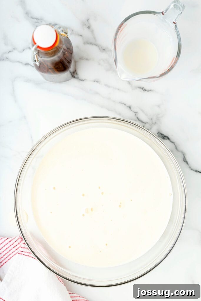 Classic Homemade Eggnog 19 Smooth strained eggnog sitting in a glass mixing bowl on a marble counter.