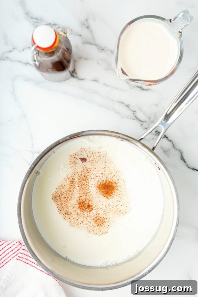 Classic Homemade Eggnog 8 Milk in a saucepan sprinkled with nutmeg and cinnamon before stirring.