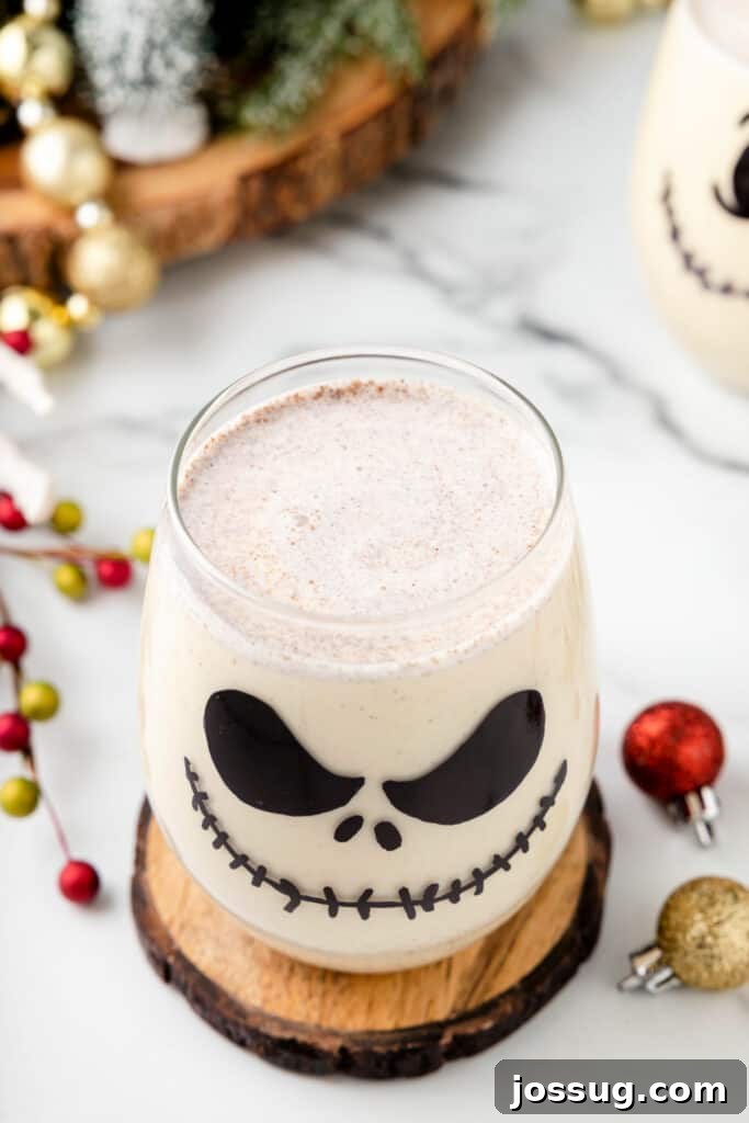 Overhead shot of a single Jack Skellington Cocktail in a decorated glass, surrounded by ornaments and greenery, capturing the festive Halloween and Christmas crossover theme.