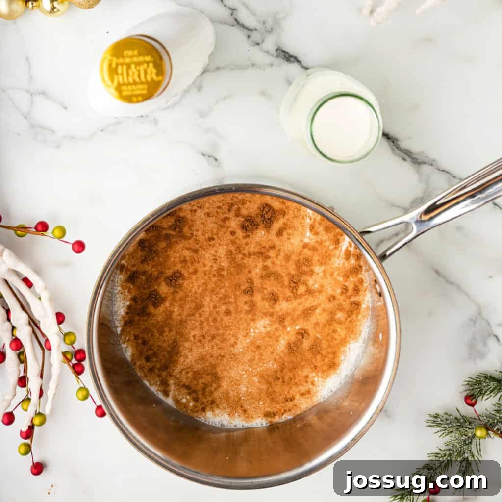 Pumpkin spice sprinkled into a saucepan of warm milk, beginning to simmer with festive decorations around the pan.