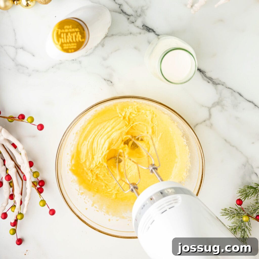 Bowl of egg yolk and sugar mixture whipped into a fluffy, pale yellow consistency with a hand mixer.