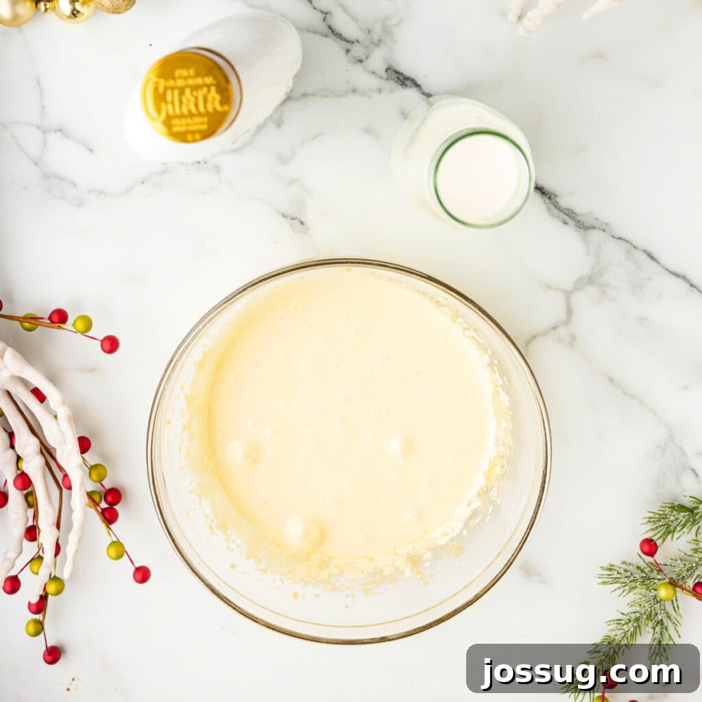 Lightened egg yolk mixture smoothed into a frothy batter in a glass bowl.