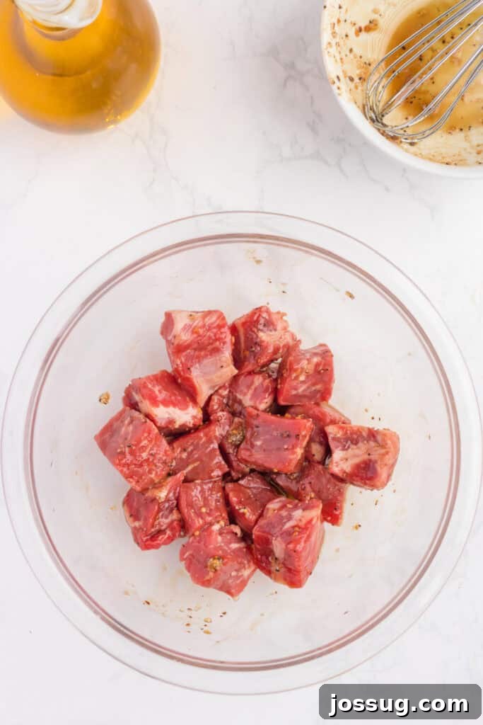 Crispy Air Fryer Steak Bites 6 Steak cubes in a glass bowl thoroughly coated with savory marinade, waiting to be cooked in the air fryer.