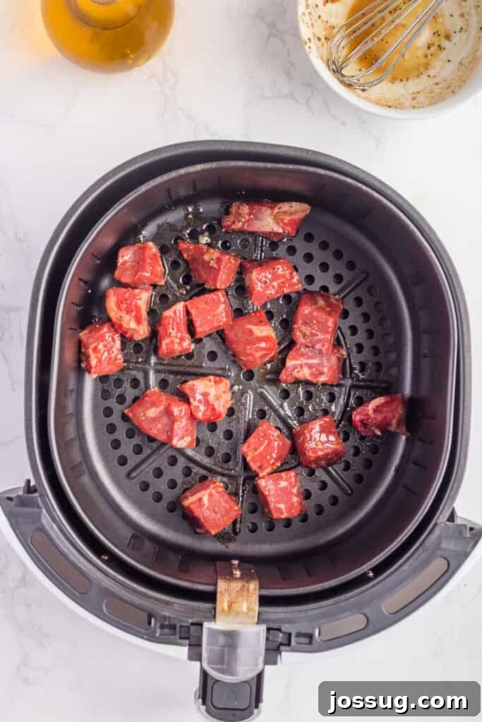 Crispy Air Fryer Steak Bites 7 Marinated steak cubes arranged in a single, uncrowded layer inside an air fryer basket before cooking, ensuring even air circulation.
