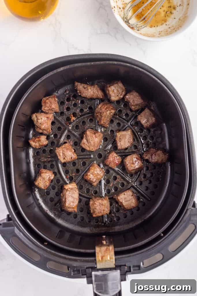 Crispy Air Fryer Steak Bites 8 Cooked steak bites in the air fryer basket, beautifully browned on the outside and promising a juicy interior.