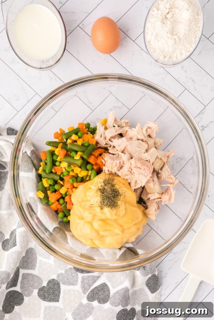 Mixing bowl with chicken, vegetables, and cream of chicken soup, combined with dried thyme.