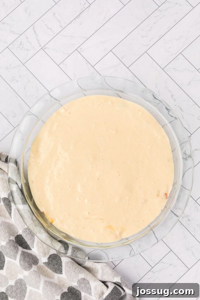 Biscuit topping spread evenly over the chicken and vegetable filling in a pie dish.