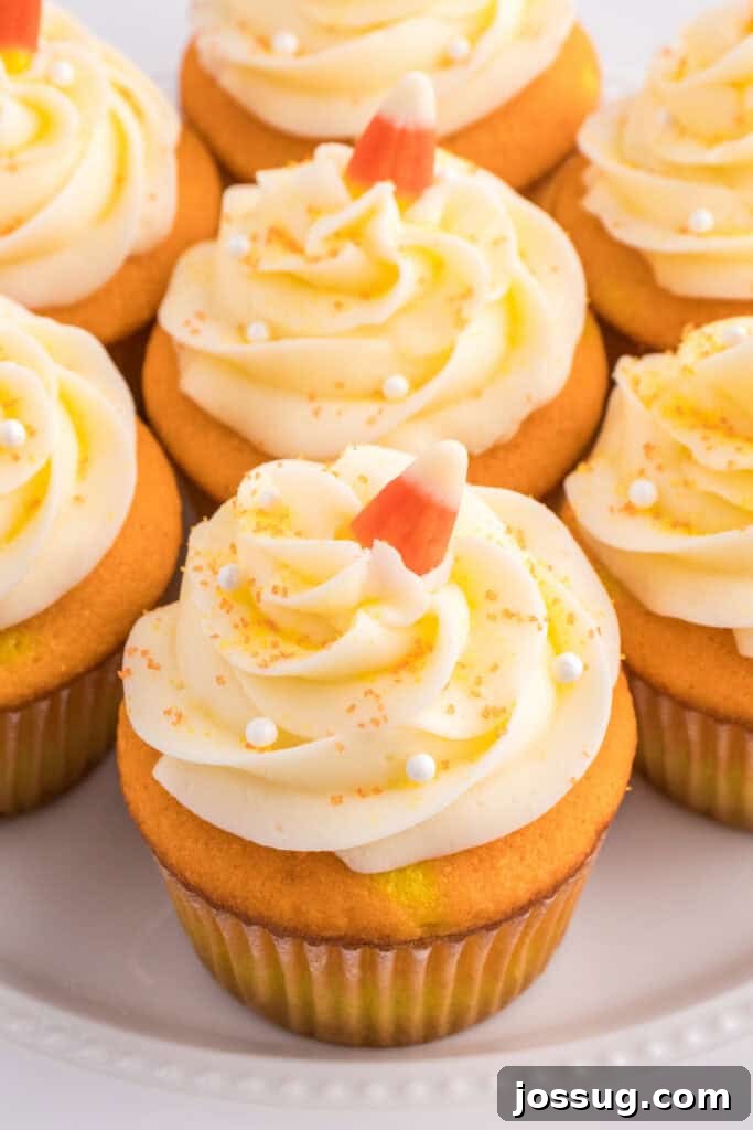 Close-up of frosted Candy Corn Cupcakes topped with white frosting swirls, candy corn, and sugar pearls.