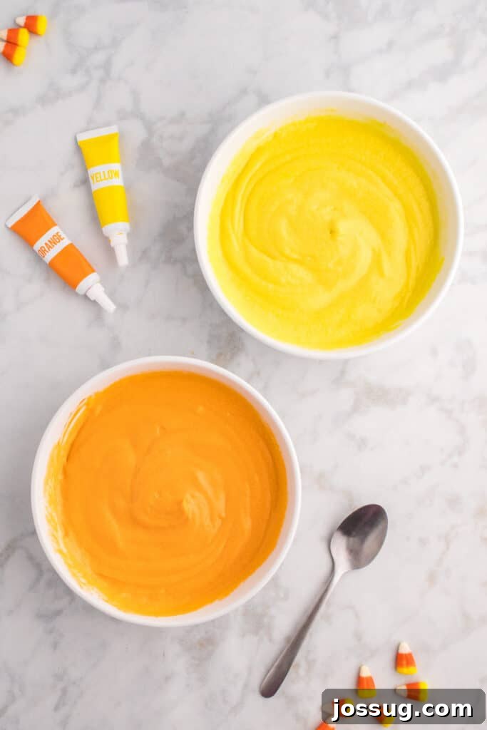Two bowls of cupcake batter now fully colored - one bright yellow and one vivid orange - ready to be layered.