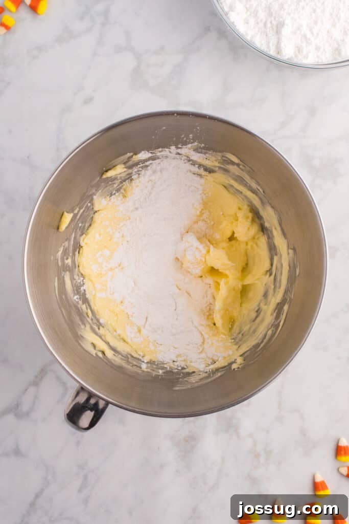 Butter being creamed with powdered sugar in a mixing bowl to make frosting.