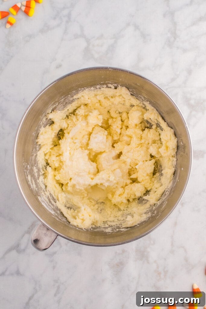 Frosting mixture in progress showing combined butter, cream, and vanilla partially mixed.