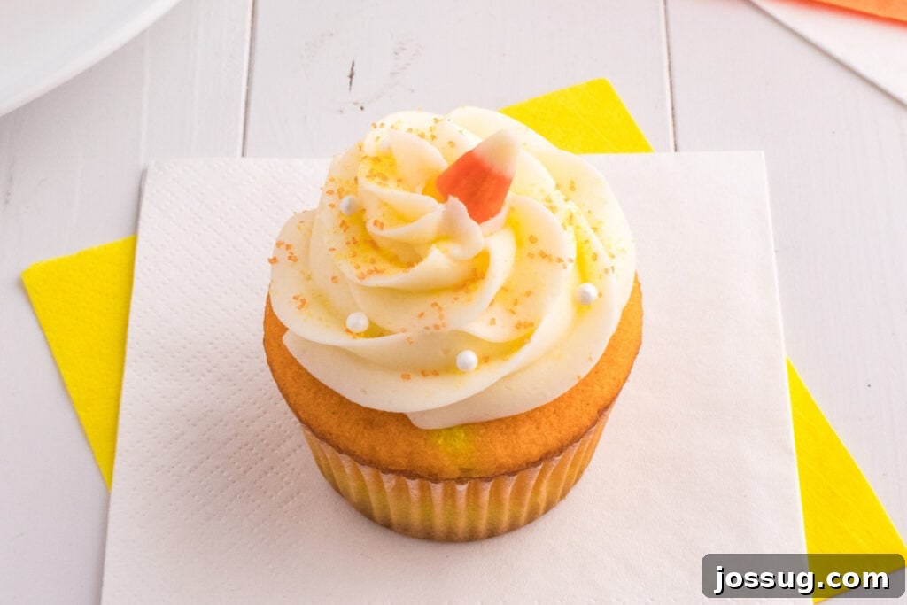 Single Candy Corn Cupcake on a napkin with yellow and white background showing detailed frosting and toppings.