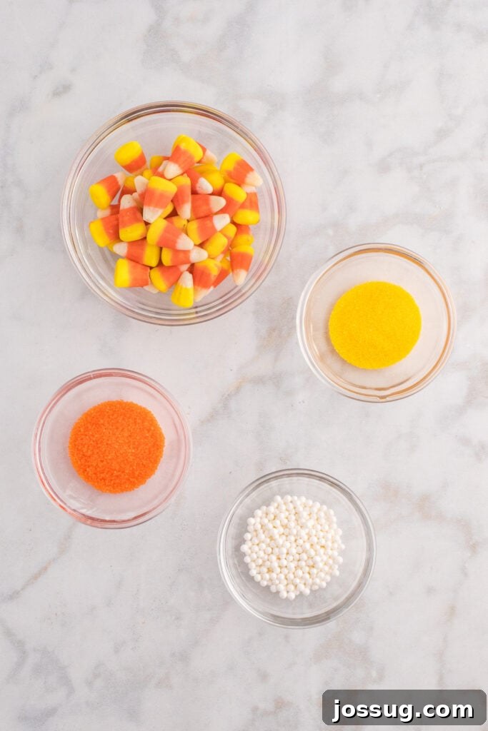 Small glass bowls filled with candy corn, orange sanding sugar, yellow sanding sugar, and white sugar pearls for decorating.