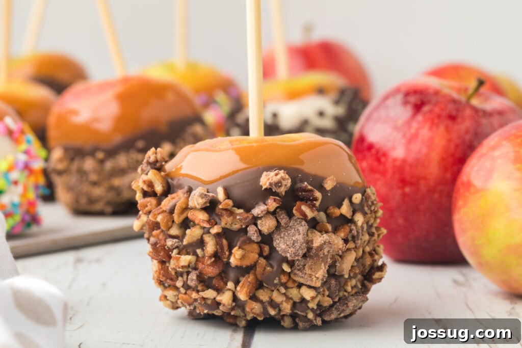 A homemade caramel apple generously coated with chopped candy bar pieces, ready to be enjoyed.