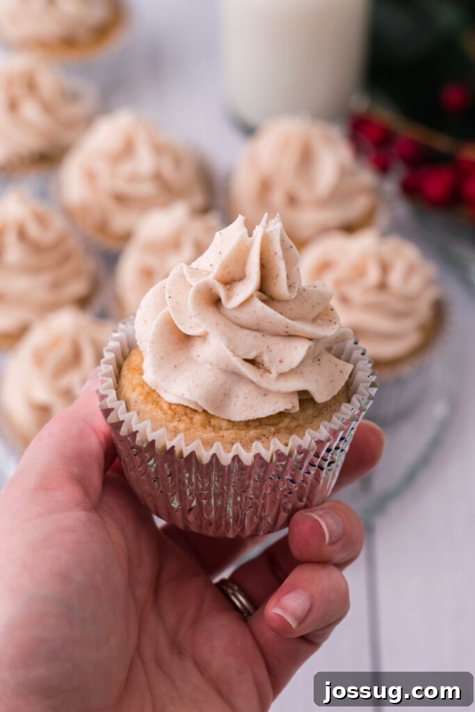 A hand gently holding a frosted Snickerdoodle Cupcake