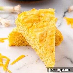 Overhead view of perfectly sliced Cheddar Onion Cornbread in a cast iron skillet with a crisp, golden crust.