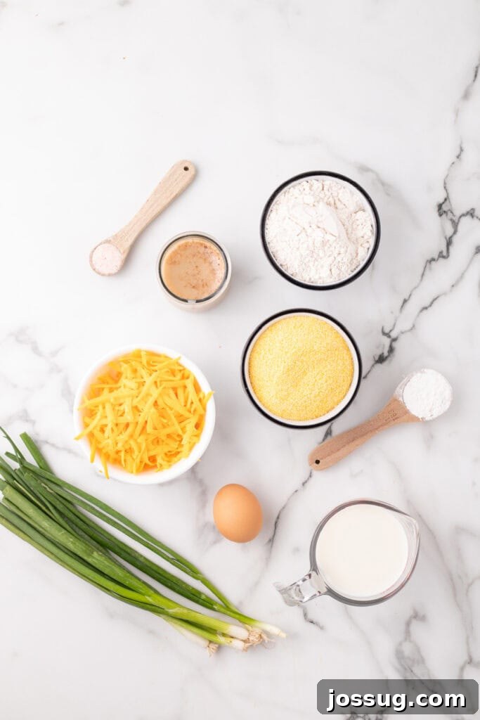 Savory Cheddar Onion Cornbread 3 Ingredients for Cheddar Onion Cornbread neatly arranged on a marble surface, featuring flour, cornmeal, shredded cheese, milk, egg, and vibrant green onions.