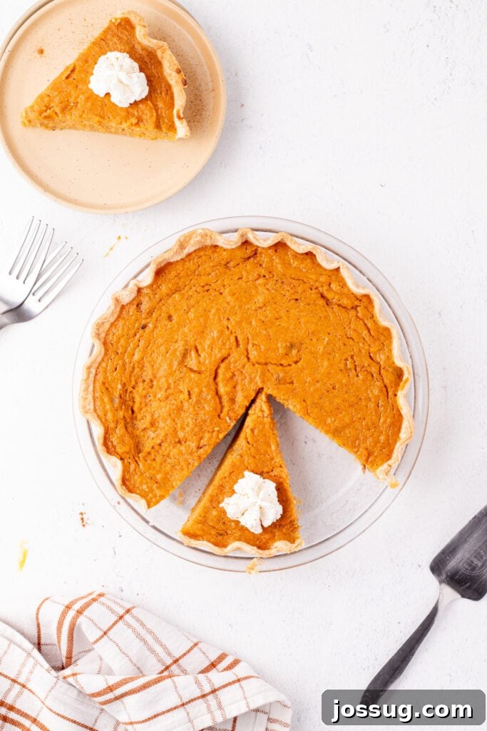 Sunshine Sweetness Pie 9 Sweet potato pie slice topped with whipped cream on a plate next to the rest of the pie.