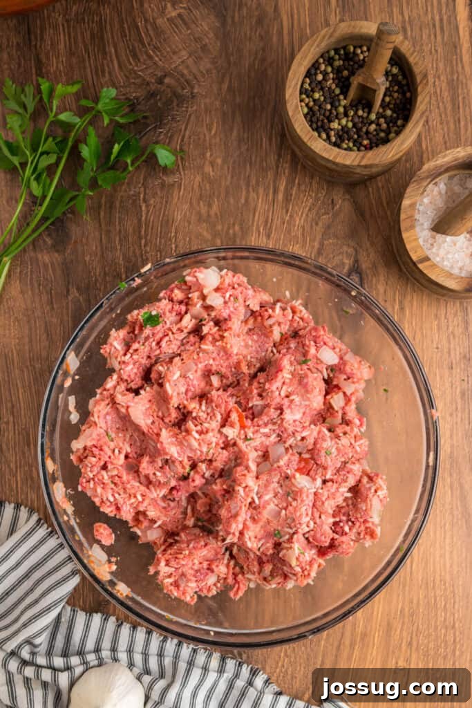 Meat mixture for the Cabbage Rolls fully mixed with rice, onions, and parsley in a glass bowl.