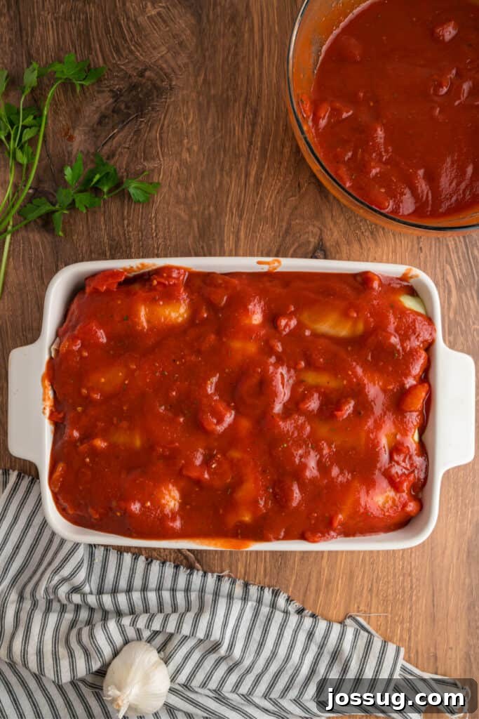 Baking dish filled with cabbage rolls completely covered in tomato sauce, ready to go in the oven.