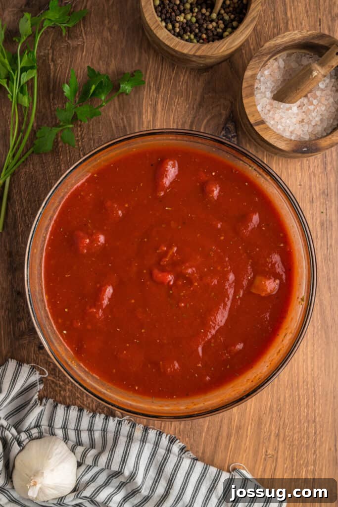 Prepared tomato sauce mixture in a glass bowl, showing blended diced tomatoes, tomato sauce, and seasonings.
