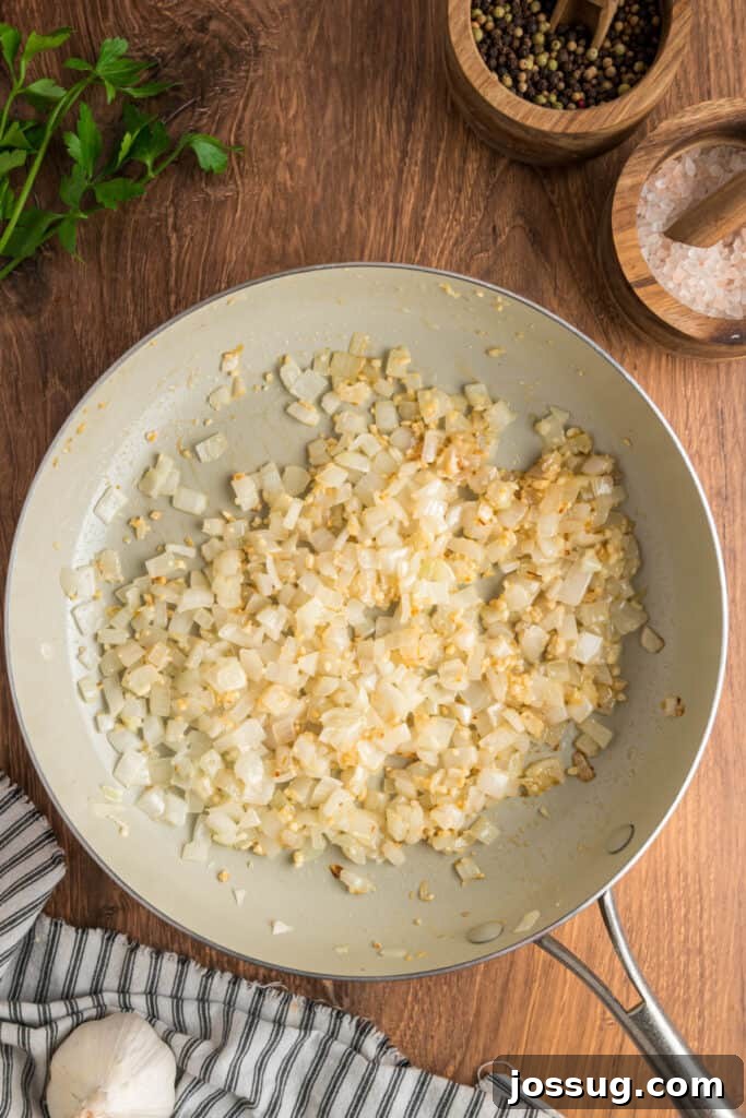 Sautéed onions and garlic in a skillet, softened and lightly golden brown, ready for the filling mixture.