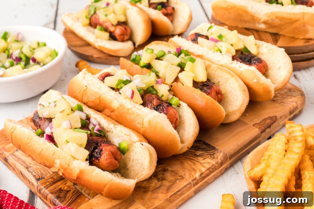 Four perfectly grilled Hawaiian Hot Dogs with vibrant pineapple salsa topping