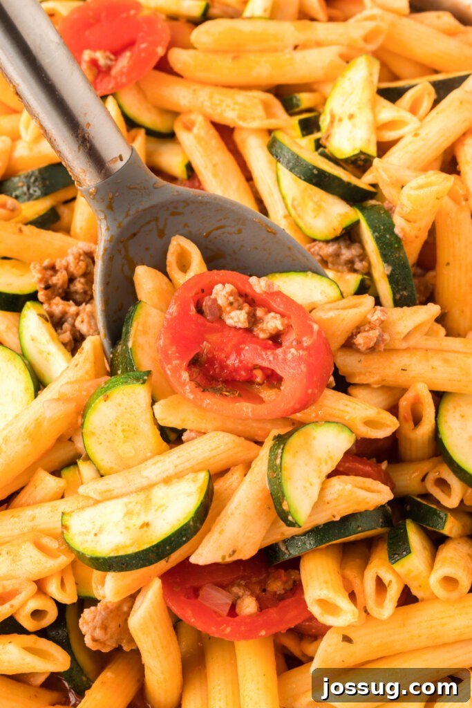 Savory Pork and Zucchini Skillet Meal 3 Close-up of a serving of pork zucchini skillet dinner, showing pasta, pork, and zucchini in rich sauce