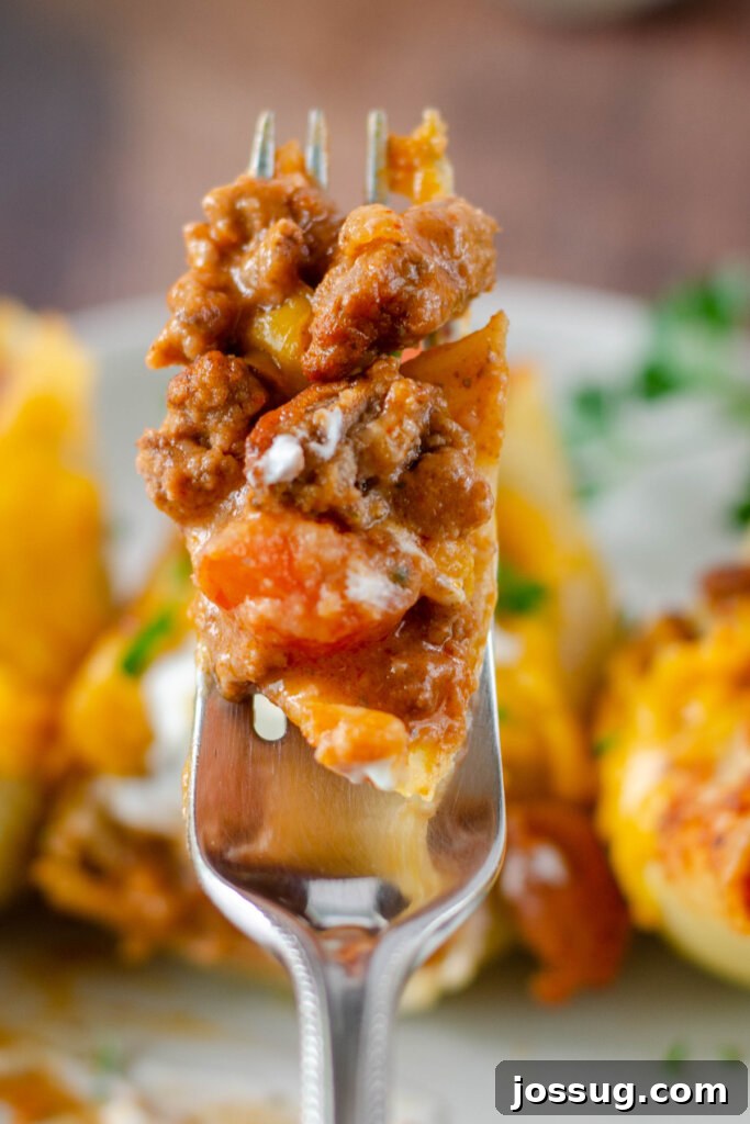 A single Enchilada Stuffed Shell perfectly balanced on a fork, showcasing the rich filling.