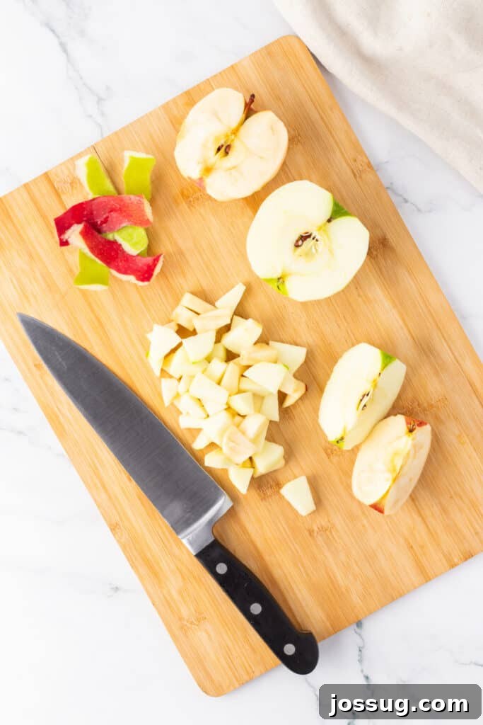 Spiced Apple Crumble Cheesecake Delights 11 A wooden cutting board with a sharp knife and a neat pile of peeled and finely diced apples, demonstrating the meticulous preparation for the spiced apple layer.
