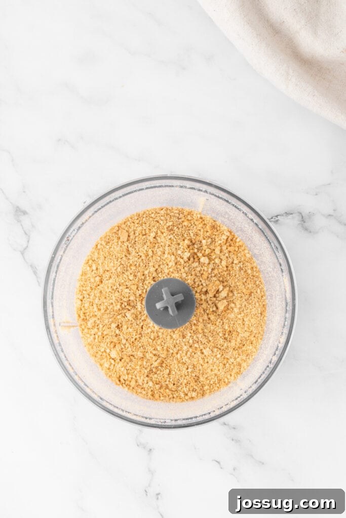 Spiced Apple Crumble Cheesecake Delights 5 Finely crushed graham cracker crumbs neatly collected in a food processor bowl after pulsing, displaying a uniform, sandy texture perfect for a cheesecake base.