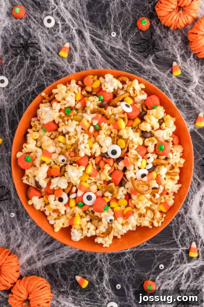 Monster Munch Popcorn 2 Finished Monster Mash Popcorn in an orange bowl surrounded by candy corn, candy pumpkins, and fake spiders on a spiderweb tablecloth.