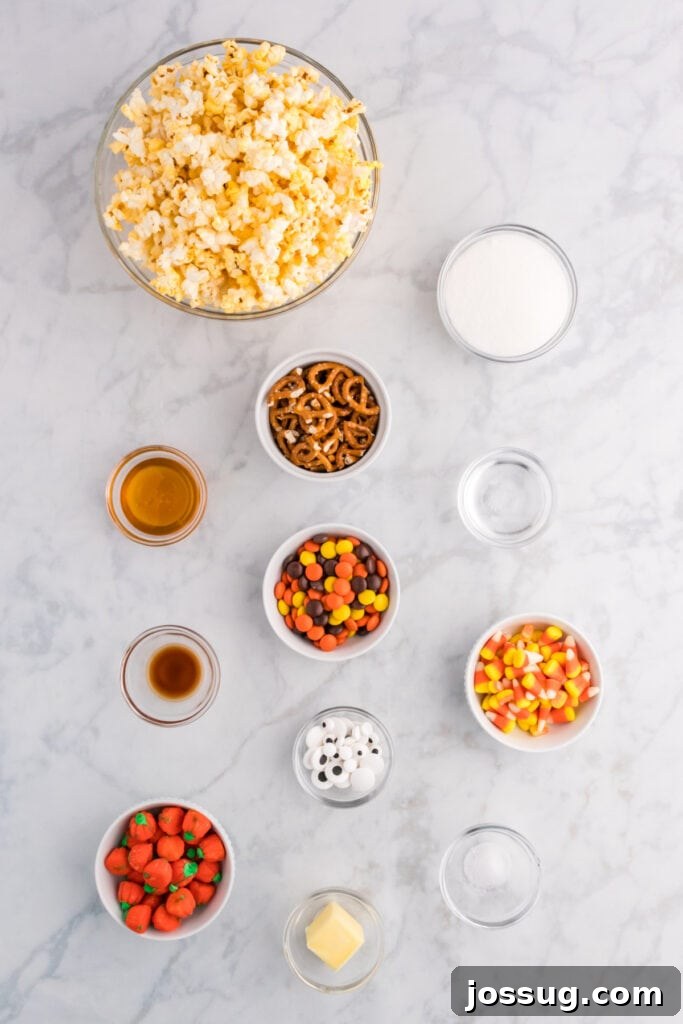 Monster Munch Popcorn 3 Overhead view of ingredients for Monster Mash Popcorn including popcorn, sugar, butter, honey, pretzels, candy corn, candy pumpkins, Reeseās pieces, candy eyeballs, and vanilla on a marble surface.