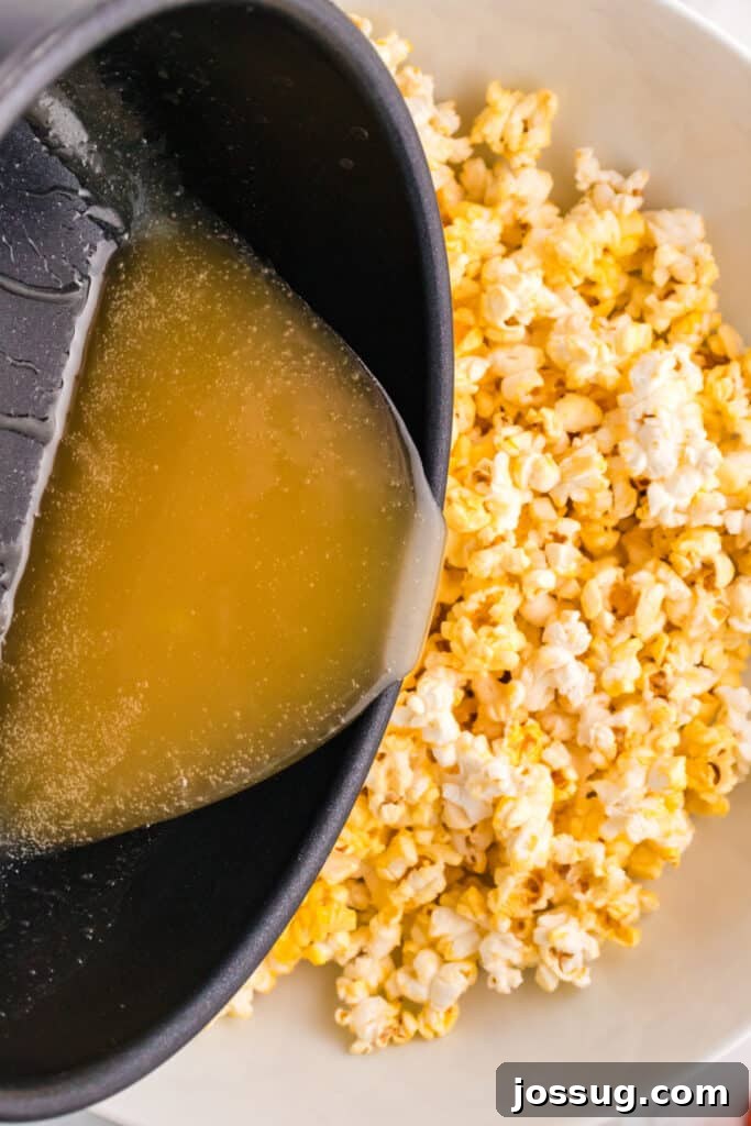 Monster Munch Popcorn 6 Hot syrup being poured from a saucepan over a large bowl of popcorn to coat it evenly.