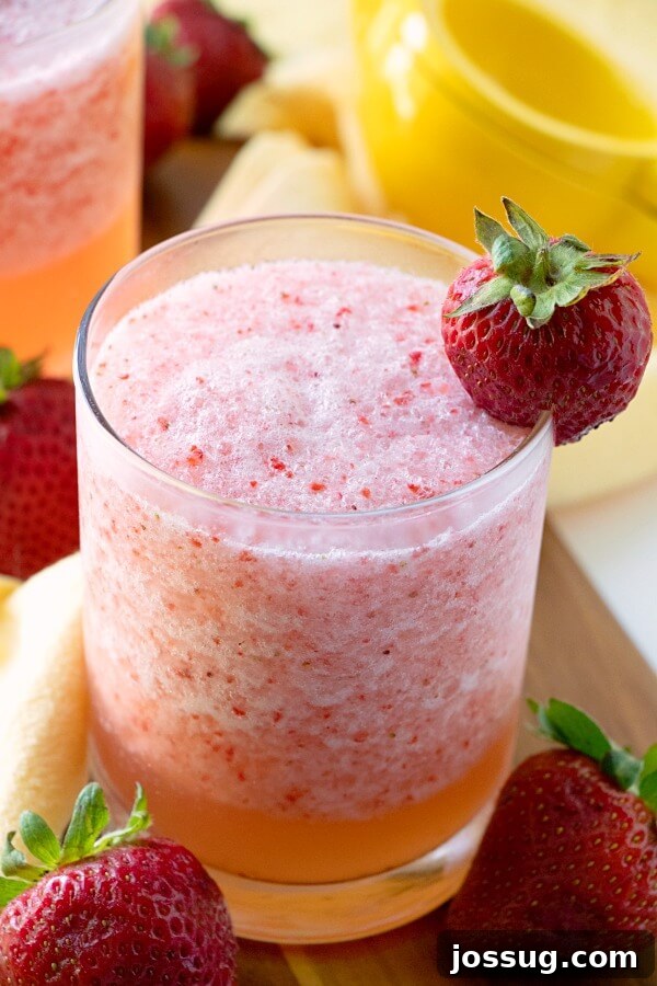 Zesty Berry Fruit Freeze 2 A glass of vibrant Lemon Berry Fruit Slush, garnished with a fresh strawberry, ready to be enjoyed on a hot day.