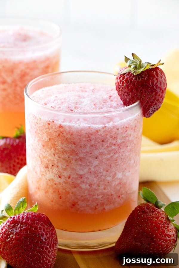 Zesty Berry Fruit Freeze 4 Close-up of a glass of Lemon Berry Fruit Slush, garnished with a single strawberry, showcasing the icy texture.