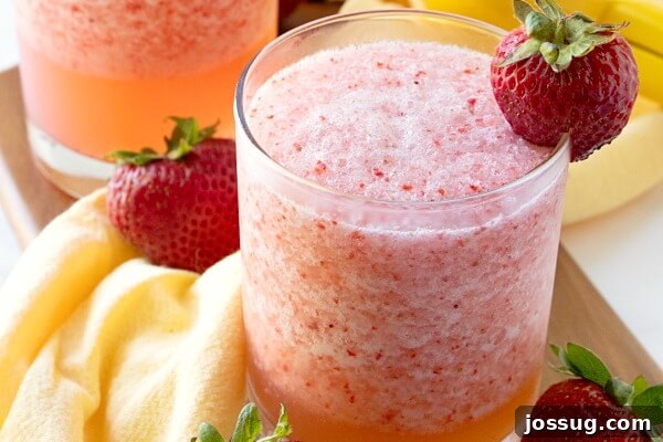 Zesty Berry Fruit Freeze 5 Refreshing Lemon Berry Fruit Slush in a glass, with a strawberry garnish and soft focus background.