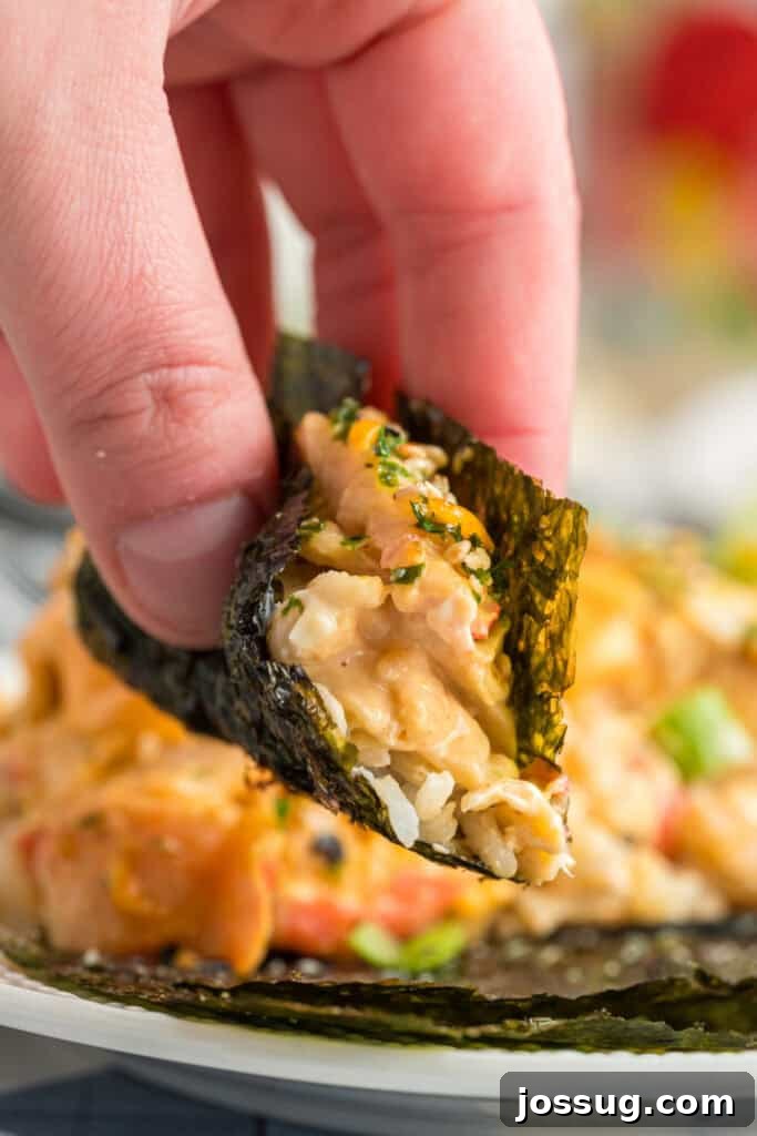 Homemade Sushi Bake Delight 2 Hand holding a bite of sushi bake wrapped in a piece of nori seaweed for serving.