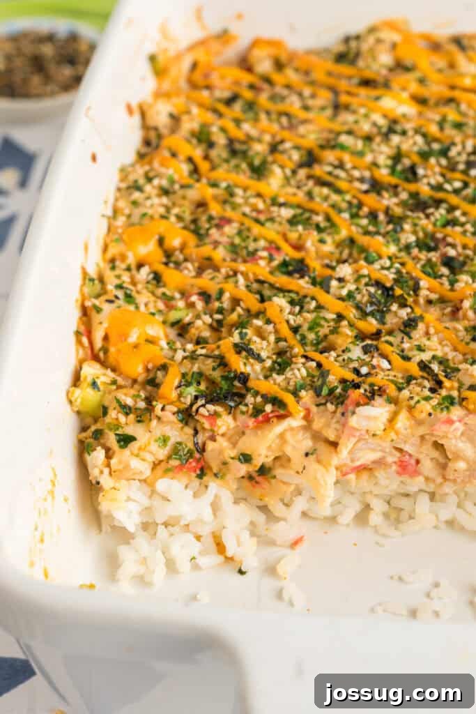 Homemade Sushi Bake Delight 14 Close-up of a partially scooped sushi bake showing layers of rice, creamy crab filling, and spicy mayo topping.