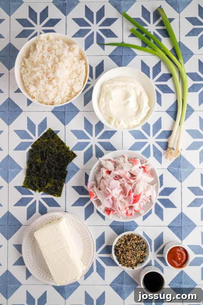 Homemade Sushi Bake Delight 3 Overhead shot of sushi bake ingredients on a blue and white tiled surface, including sushi rice, crab sticks, cream cheese, mayonnaise, soy sauce, sriracha, furikake, and green onions.