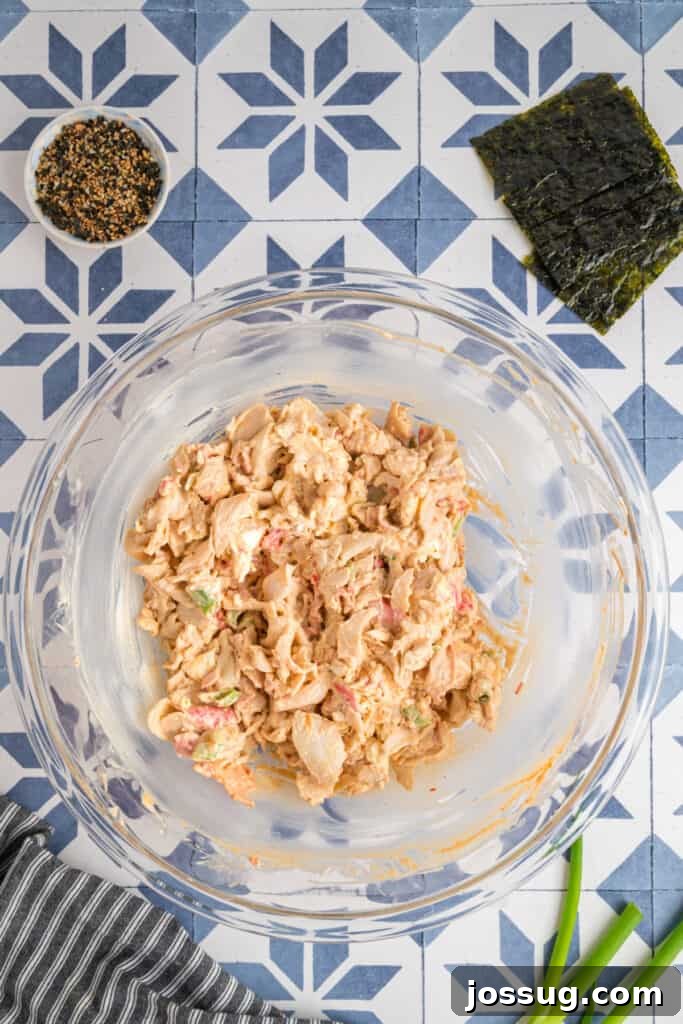 Homemade Sushi Bake Delight 5 Sushi bake mixture fully combined in a glass bowl, showing creamy crab and sriracha filling ready to layer over rice.