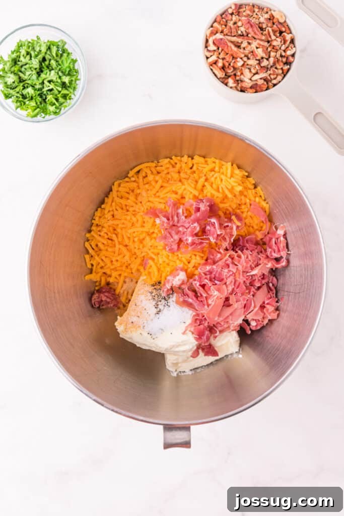Mixing bowl filled with shredded cheddar, cream cheese, and chopped prosciutto ready to be blended for Holiday Cheese Ball.