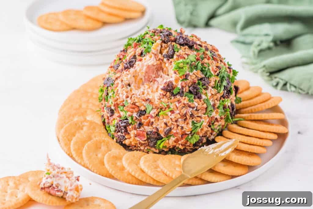 Holiday Cheese Ball on a white plate with green napkin in the background, showing texture and serving setup.
