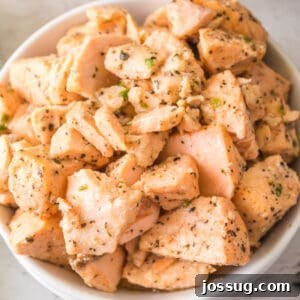 Close-up of a white bowl filled with tender, seasoned air fryer salmon bites coated in garlic butter and herbs.
