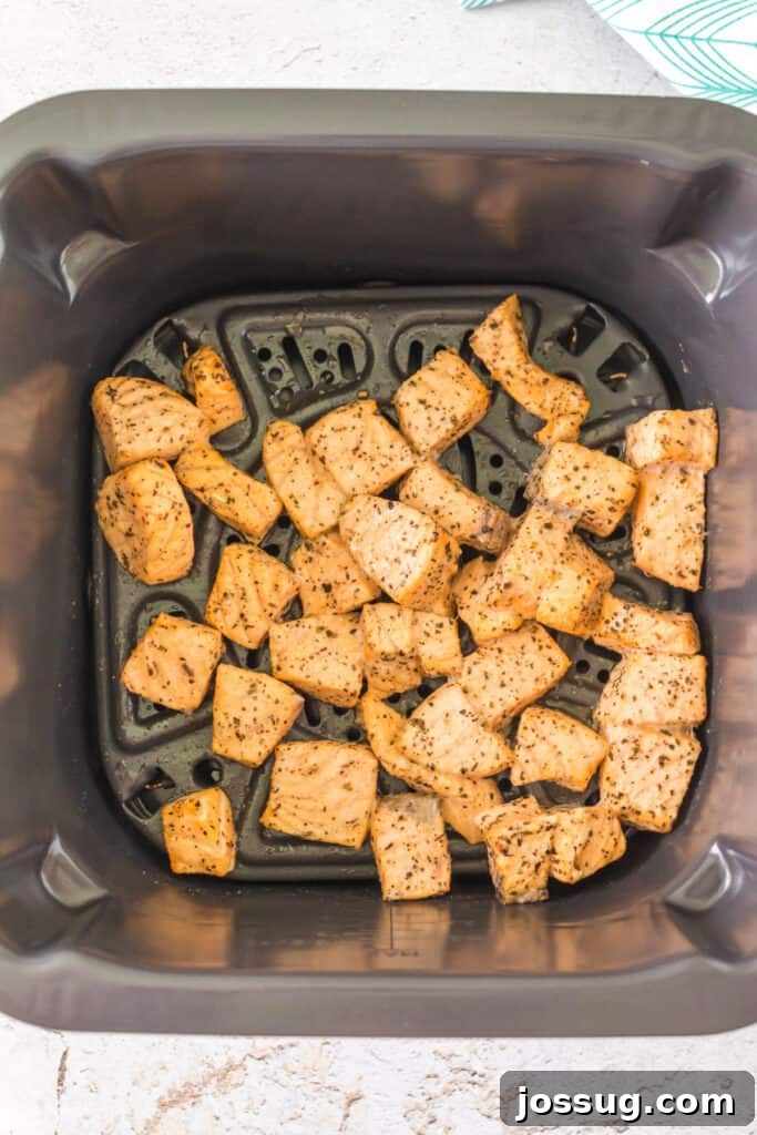 Cooked salmon bites in an air fryer basket showing golden color and crisp edges.